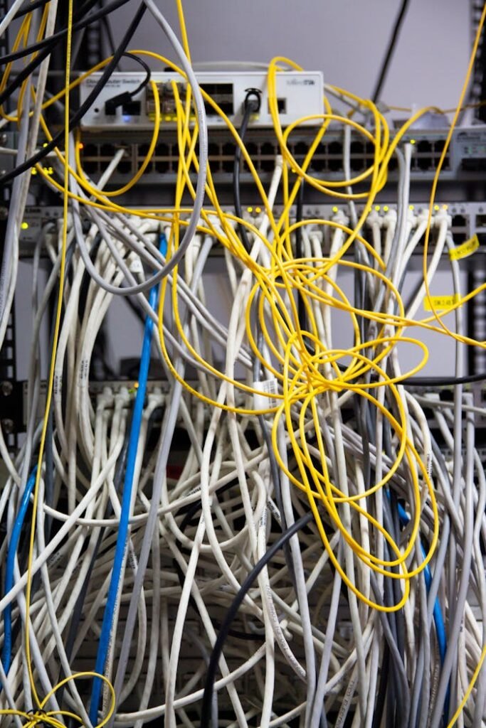 Close-up of tangled network cables and wires in a server room, showcasing technological chaos.